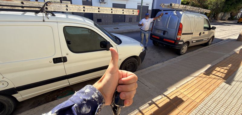 Dos camionetas de trabajo con escaleras en la vereda, antes de salir a obra